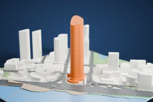 A white 3D print of 1 William Street, a tall slender oval tower with a sloping top and a thin mast, rising beside open water and low city buildings.