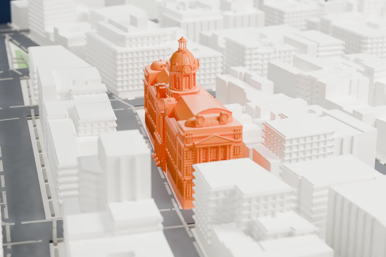 A white 3D print of 240 Centre Street, a long building with a large central dome and smaller domes at its ends, among lower and taller city buildings.