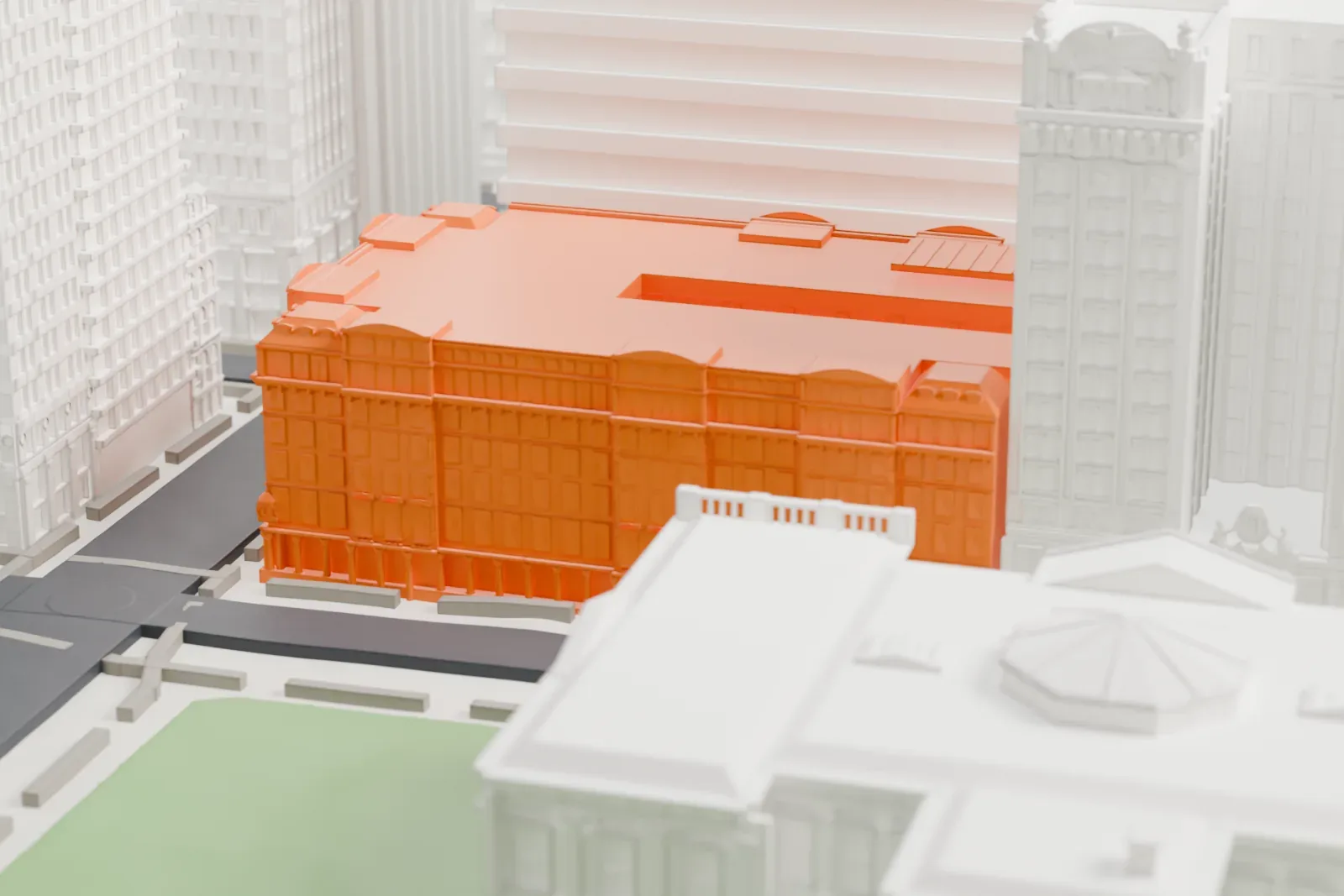 A white 3D print of 280 Broadway, a seven-story block with a richly detailed facade, next to a park and surrounded by taller buildings.
