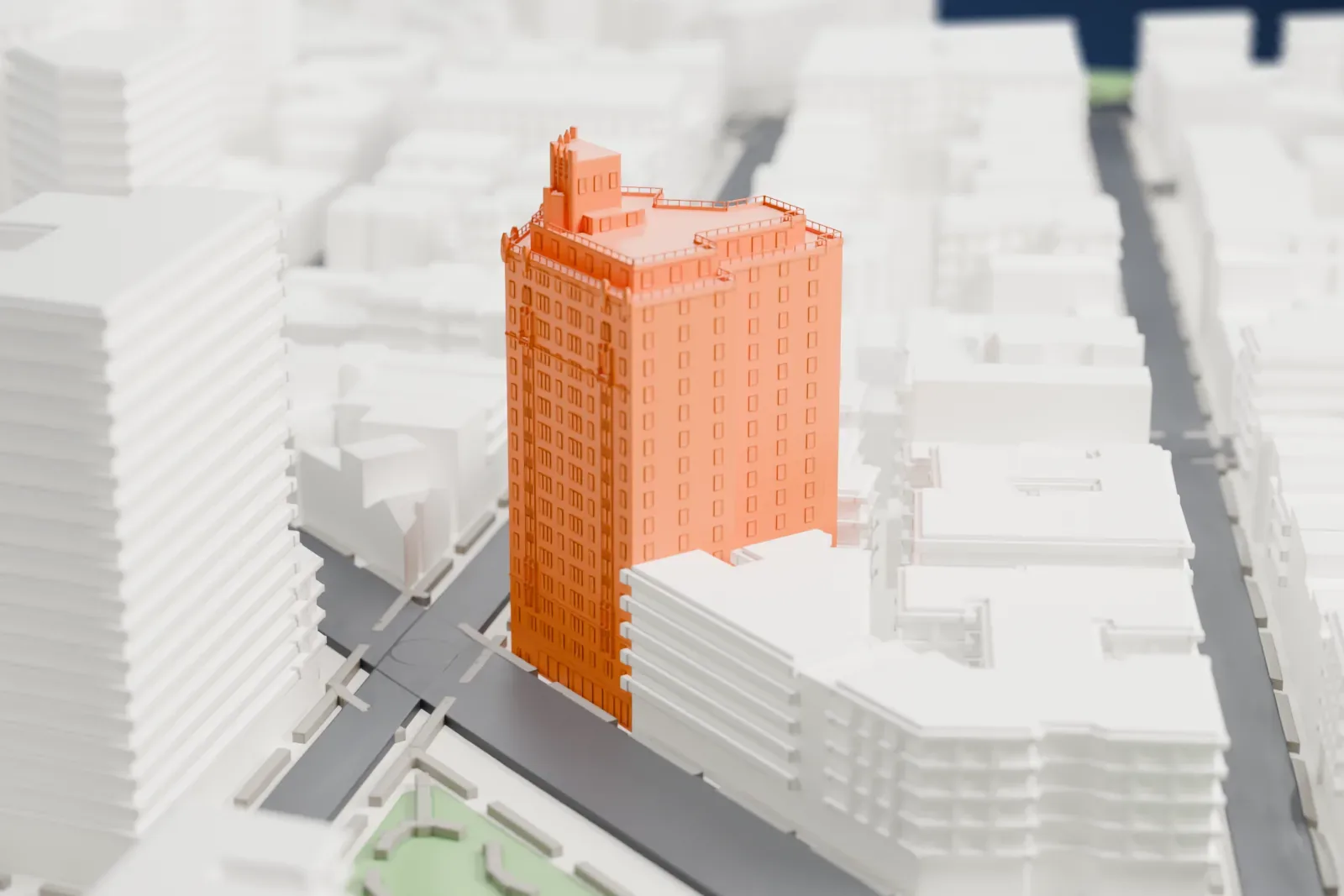 A white 3D print of 302 West 12th Street, a tall residential building with a stepped top, standing among lower buildings and streets with a small park nearby.