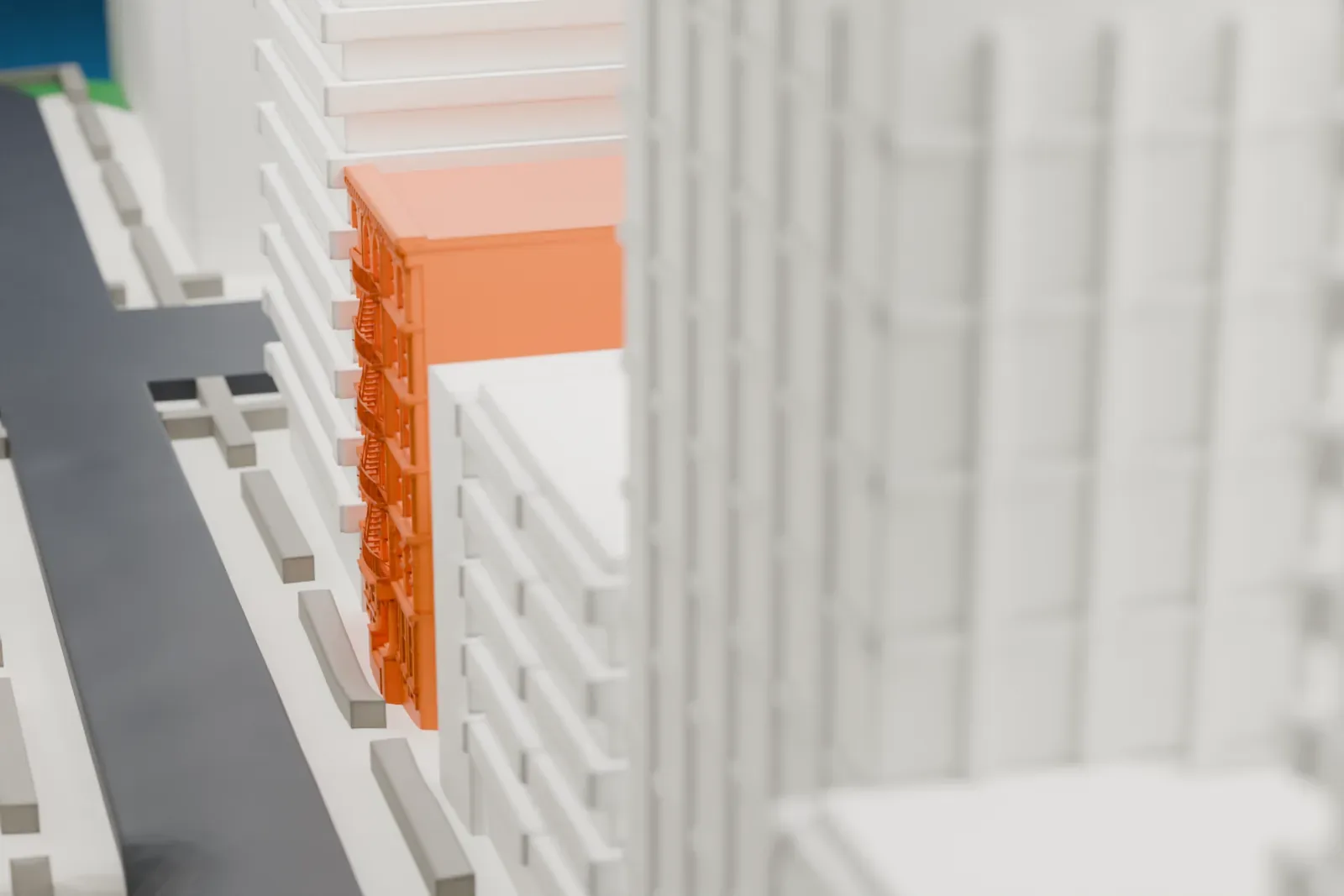 A white 3D print of 444 East 58th Street, a small building lost among tall towers, with water along the edge of the city.