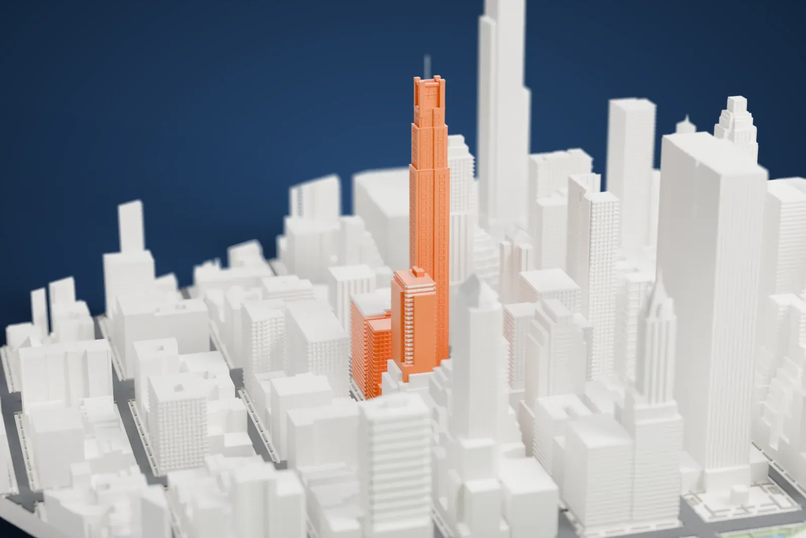A white 3D print of 520 Park Avenue, a very tall slim tower with a stepped crown, rising above a dense field of other high-rise buildings.