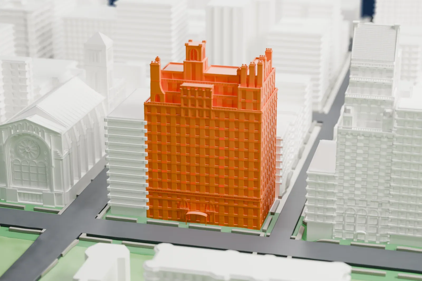 A white 3D print of 834 Fifth Avenue, a tall apartment building with stepped upper floors, beside a park and a church with a pitched roof.
