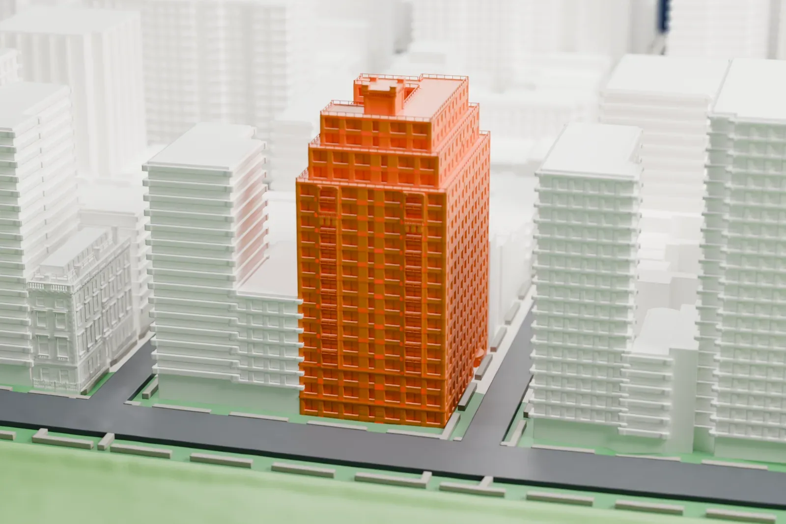 A white 3D print of 930 Fifth Avenue, a tall apartment building whose upper floors step back in tiers, beside a park with a pond and surrounded by other tall buildings.