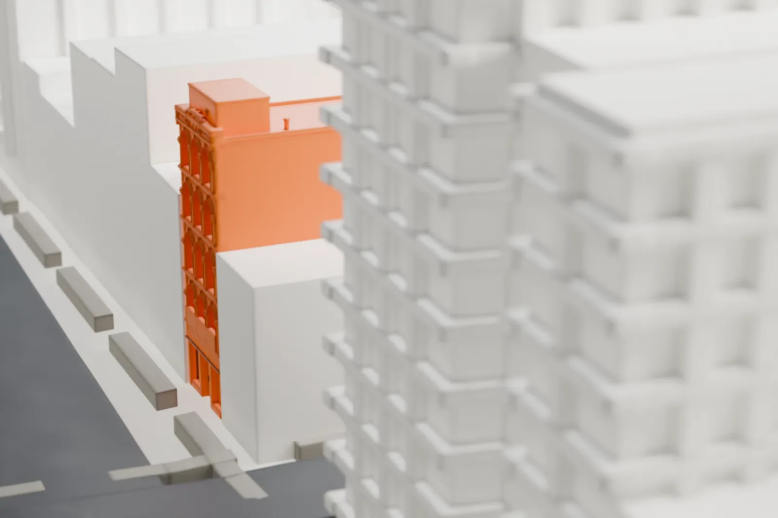 A white 3D print of 97 Bowery, a tall, narrow building with a detailed arched-window front, wedged between larger buildings.