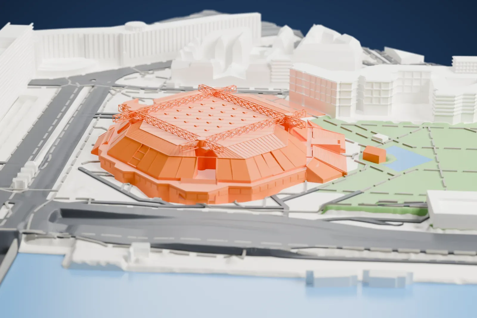 A white 3D print of Accor Arena, a low pyramid-shaped arena with sloping walls and two crossing steel trusses on its roof, beside a park and water.