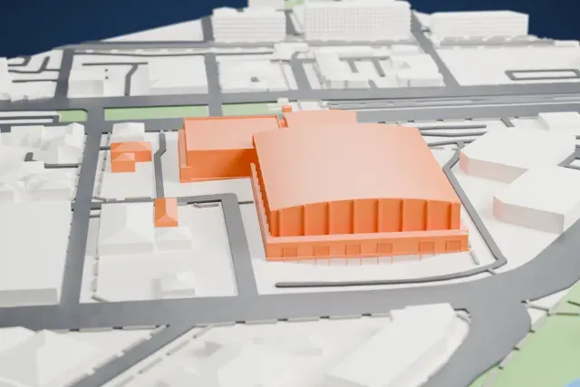A white 3D print of the Adelaide Entertainment Centre, a large arched-roof arena with a lower wing beside it, surrounded by streets and low buildings, with a waterway and green banks nearby.