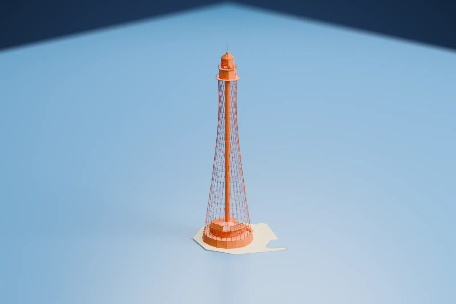 A white 3D print of the Adziogol Lighthouse, a tall open lattice tower with a small lantern on top, standing on a small islet surrounded by water.