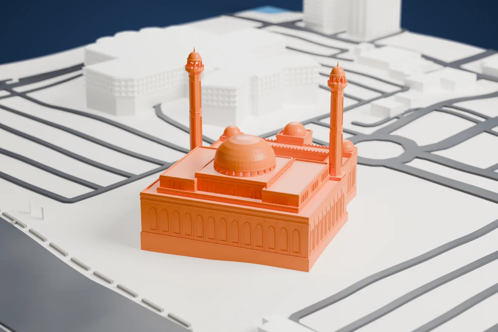 A white 3D print of the Al Fateh Grand Mosque, with a large central dome, small corner domes and two slender minarets, on open ground between roads.