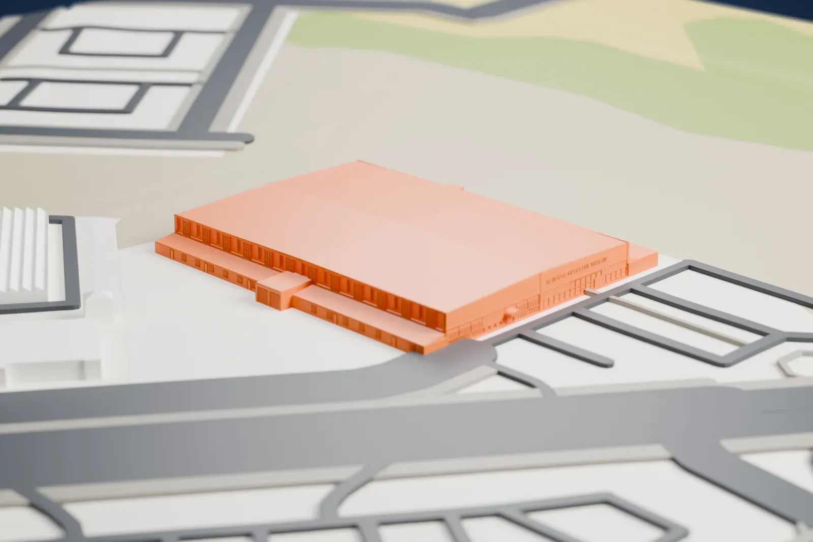 A white 3D print of the Alberta Aviation Museum with a broad pitched roof and small projecting blocks, surrounded by open ground, roads and nearby buildings.