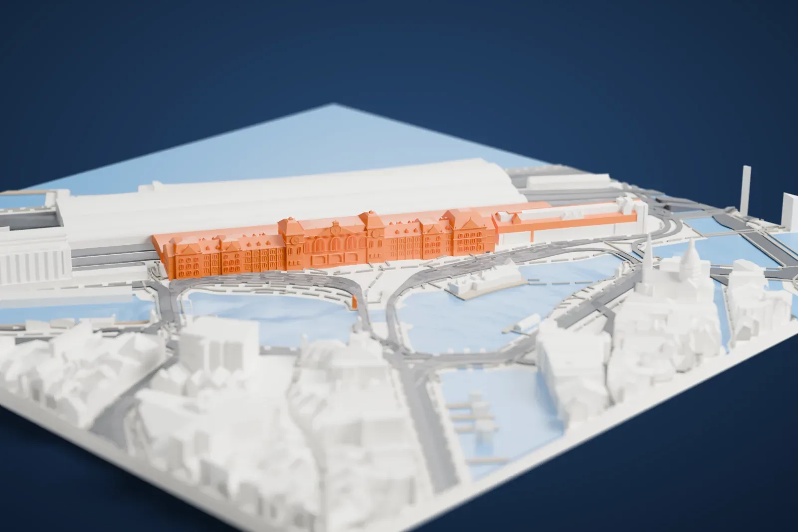 A white 3D print of Amsterdam Centraal, a long station building with turrets, gables and steep roofs beside water, with large curved platform roofs, roads and buildings around it.