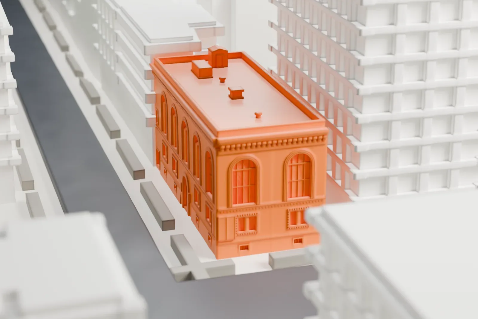 A white 3D print of Anthology Film Archives, a three-story building with tall arched windows and a cornice, set among larger buildings and streets.