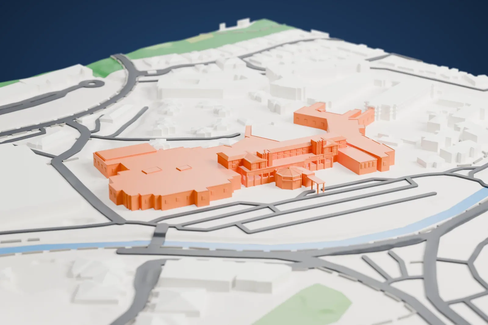 A white 3D print of the Arizona Biltmore, a sprawling many-winged low building beside a narrow waterway, with roads and small houses around it.