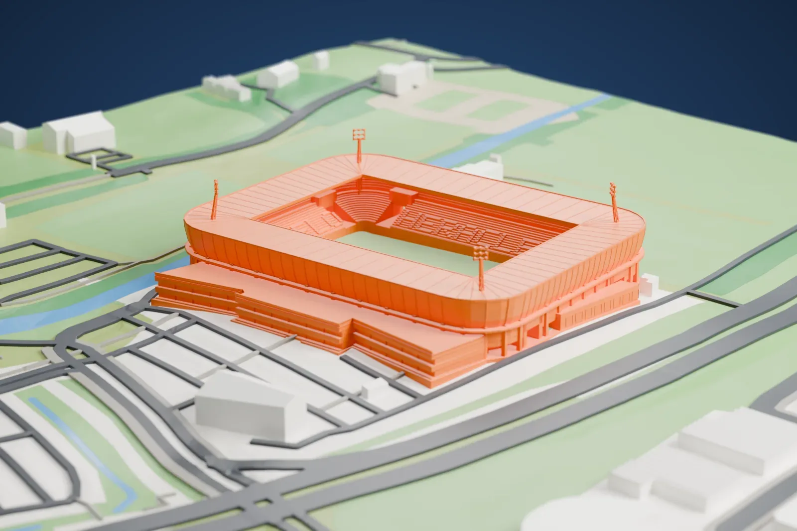 A white 3D print of Asito Stadion, a compact rectangular football stadium with an open pitch and roofed stands, among the surrounding streets and fields.
