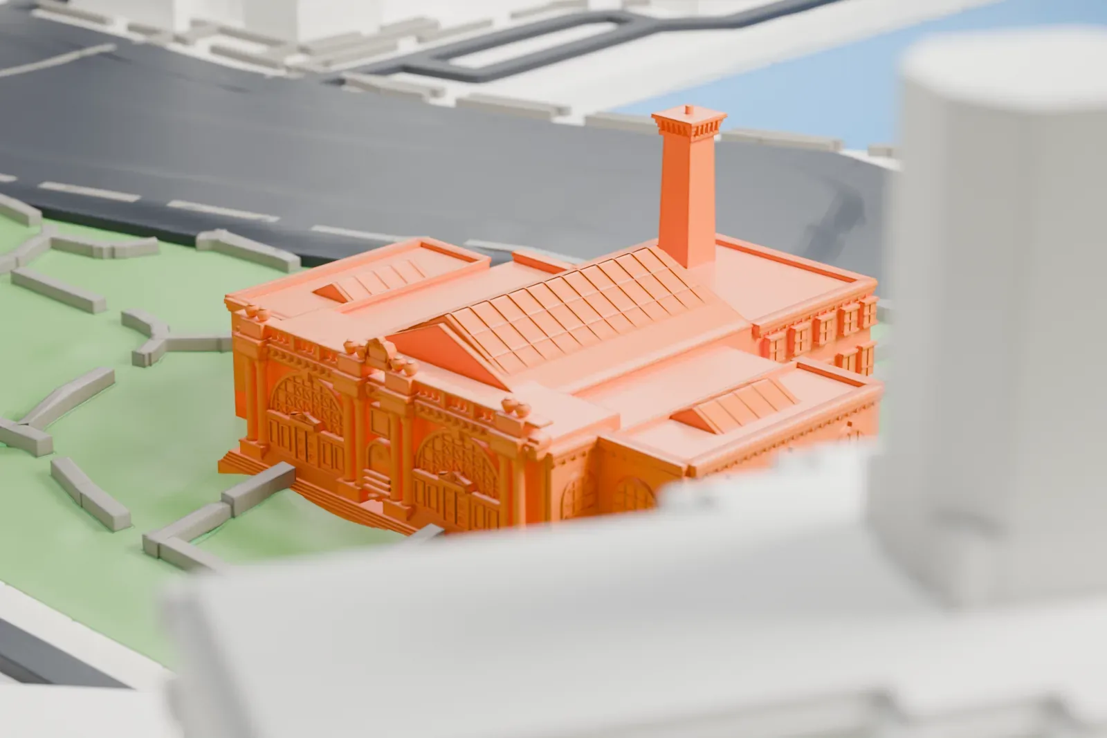 A white 3D print of the Asser Levy Recreation Center, a low bathhouse with arched windows, a skylight roof and a chimney, set in a green park beside a river with apartment towers behind.