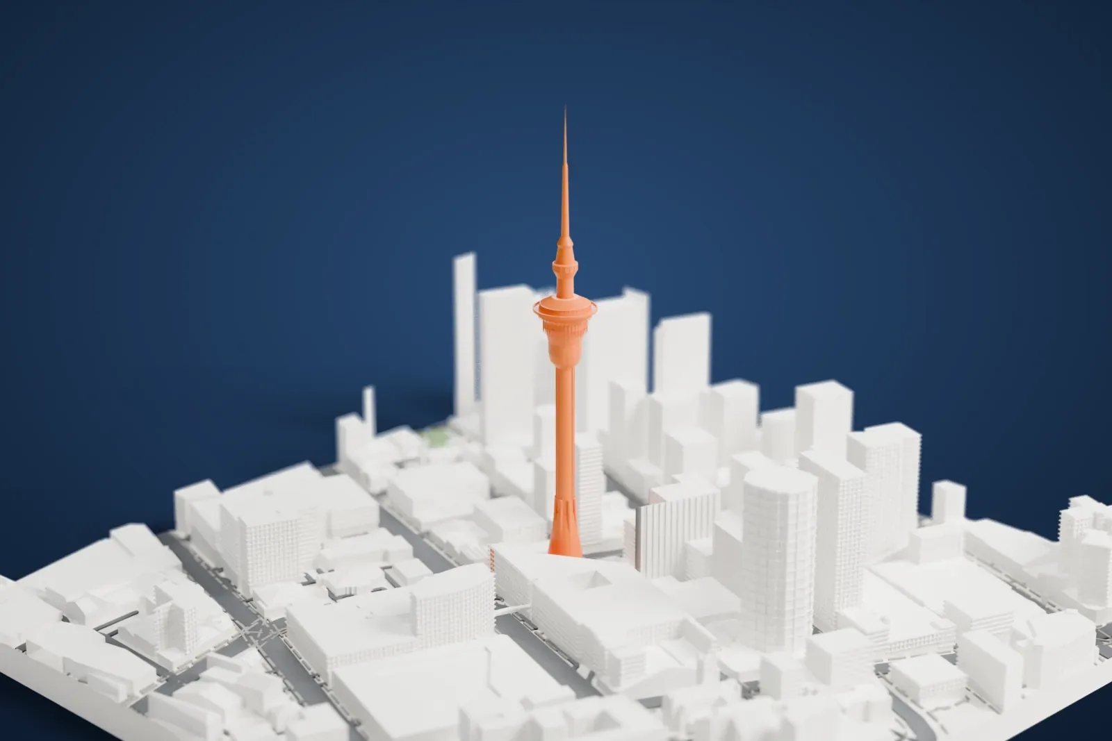 A white 3D print of the Auckland Sky Tower, a very tall slender tower with a round observation pod near the top and a thin mast above it, rising among the city's dense buildings.