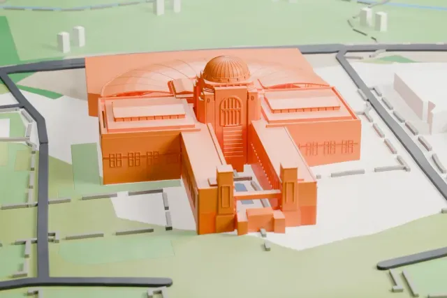 A white 3D print of the Australian War Memorial, a low building with a central dome, a rounded fan-roofed wing and long straight wings, set in green parkland with roads and a few larger buildings nearby.