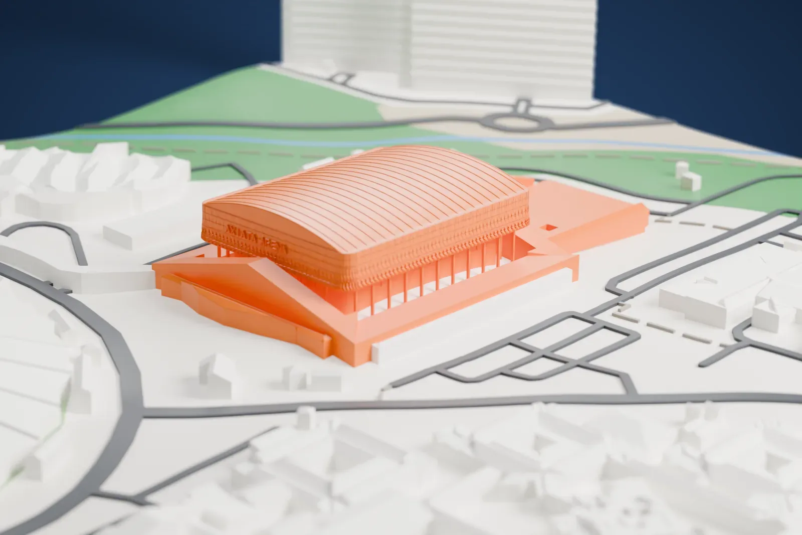 A white 3D print of Axiata Arena, a wide arena with a curved, finely ribbed roof above a lattice-patterned band and thin columns, set among low buildings, roads and open ground.