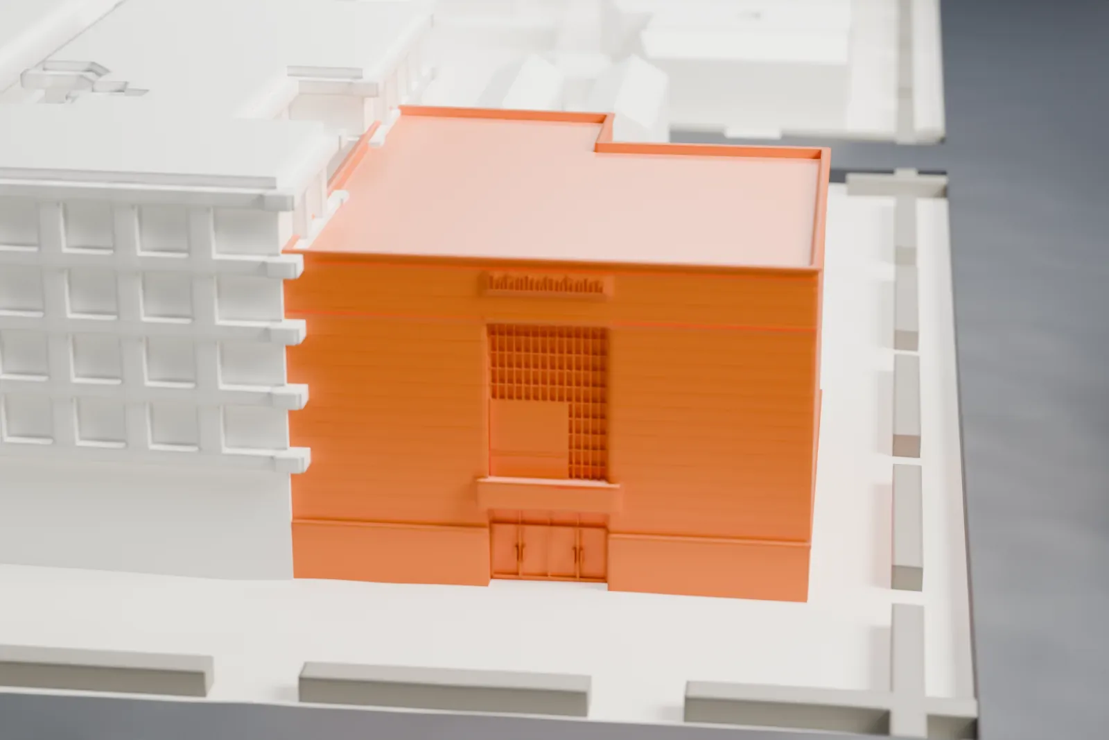 A white 3D print of B'nai Yosef Synagogue, a plain boxy building with a flat roof and an L-shaped outline, set among lower buildings and streets.