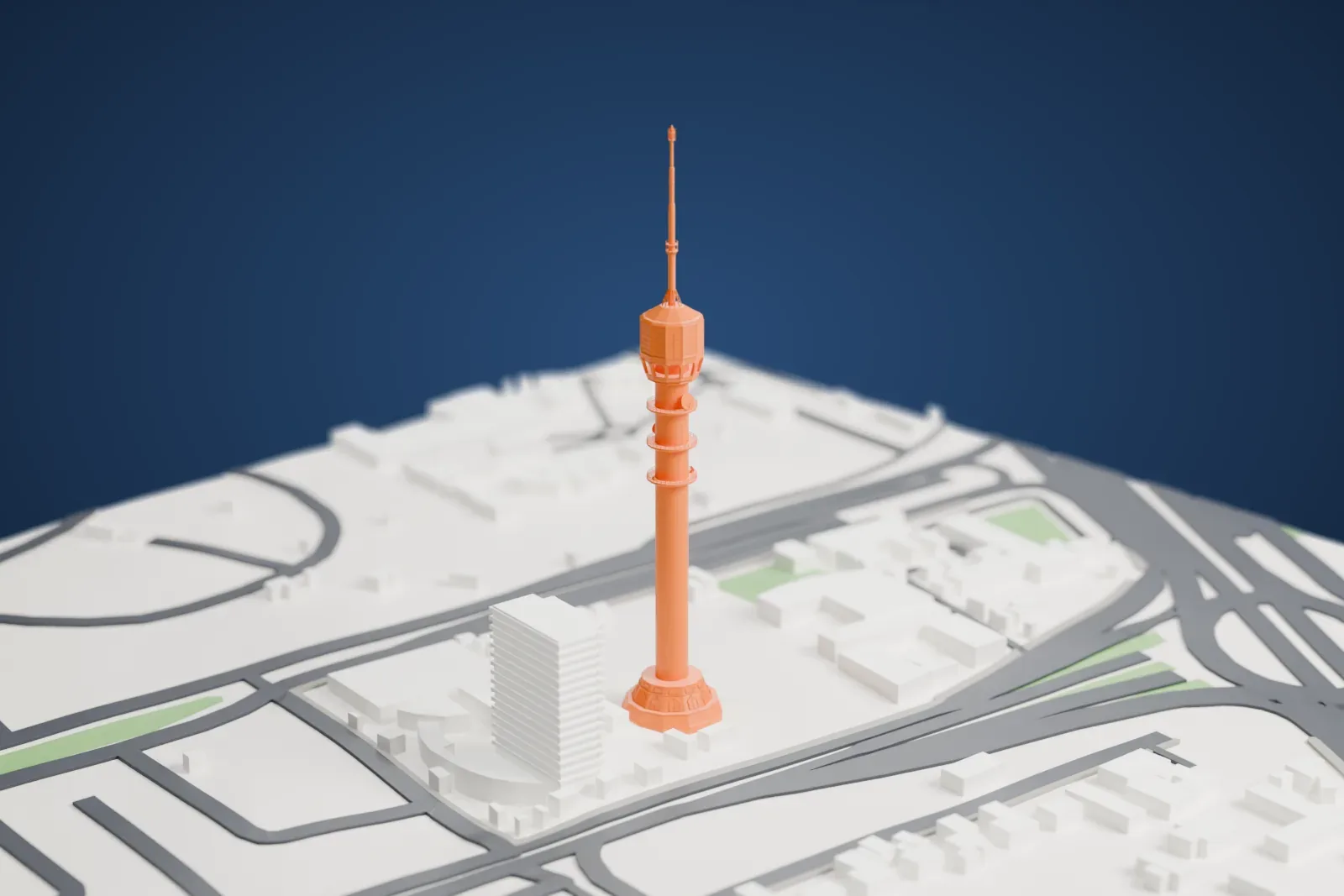 A white 3D print of Baghdad Tower, a slender tower with a round head and a tall mast, standing among surrounding streets and buildings.