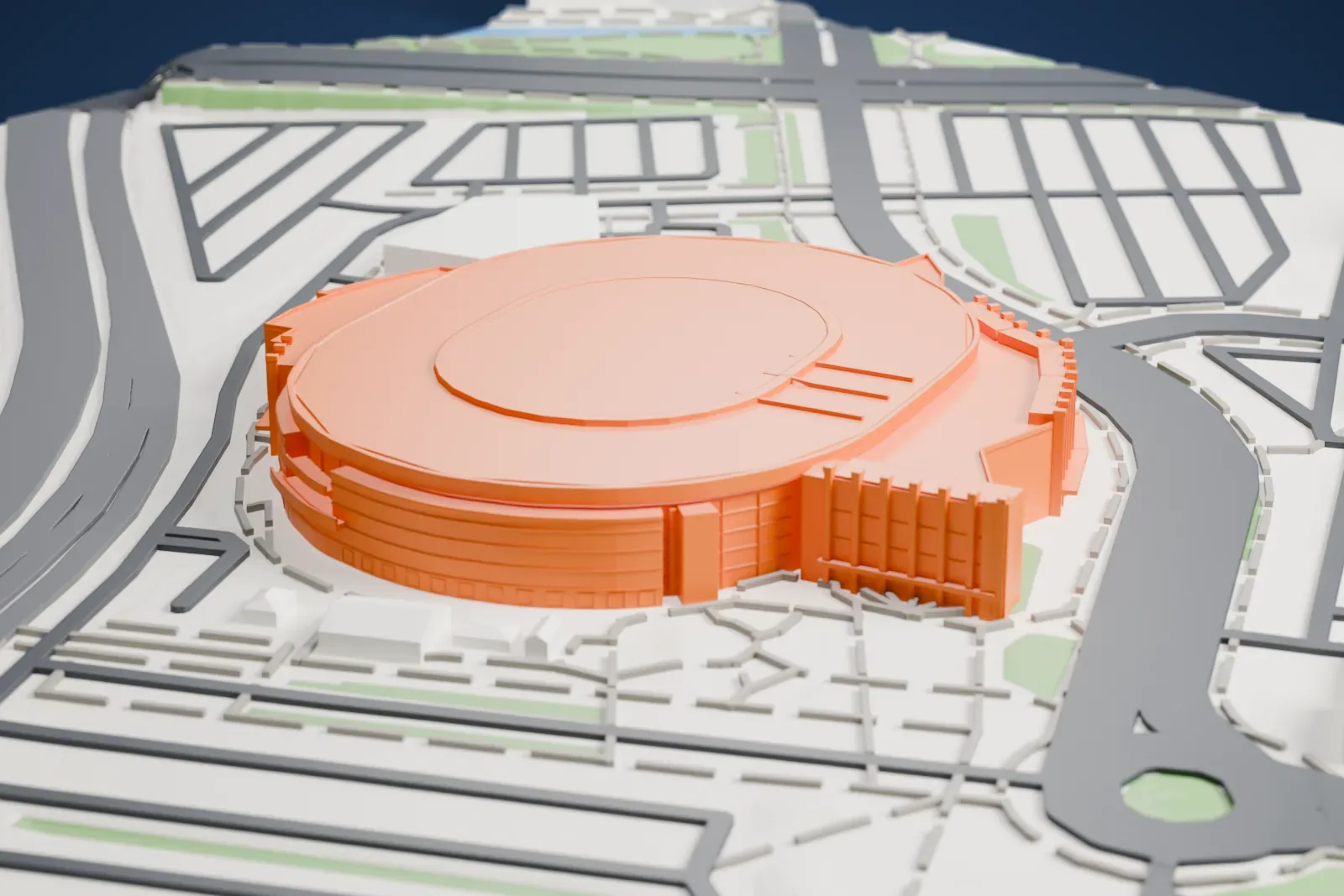 A white 3D print of Ball Arena, an oval drum with a thick overhanging roof brim and a curved shield wall at its entrance, among surrounding streets and buildings.