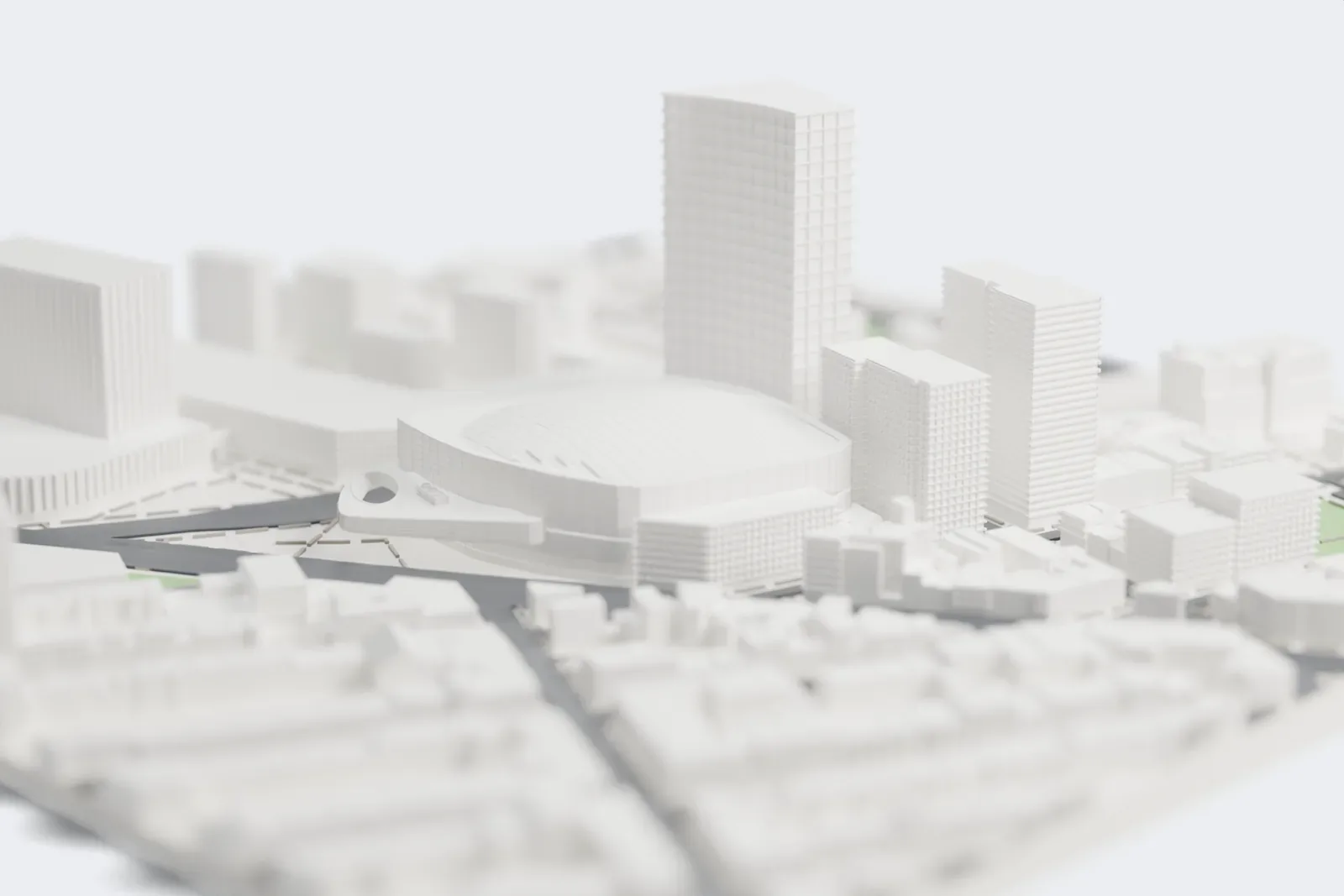 A white 3D print of Barclays Center, a wide rounded arena with a ribbed roof and a tall tower rising beside it, among dense city blocks, roads and a few small green spaces.