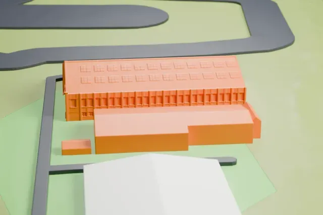 A white 3D print of the Barton Aerodrome main hangar and workshops model in Manchester, with the streets around it.