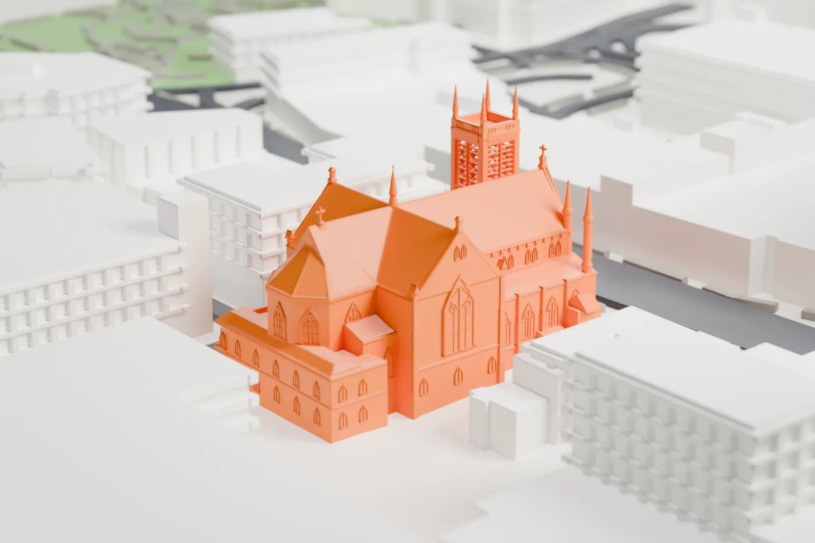 A white 3D print of the Basilica of Saint John the Evangelist, a stone church with a tall front tower and steep roofs, among streets and larger buildings.