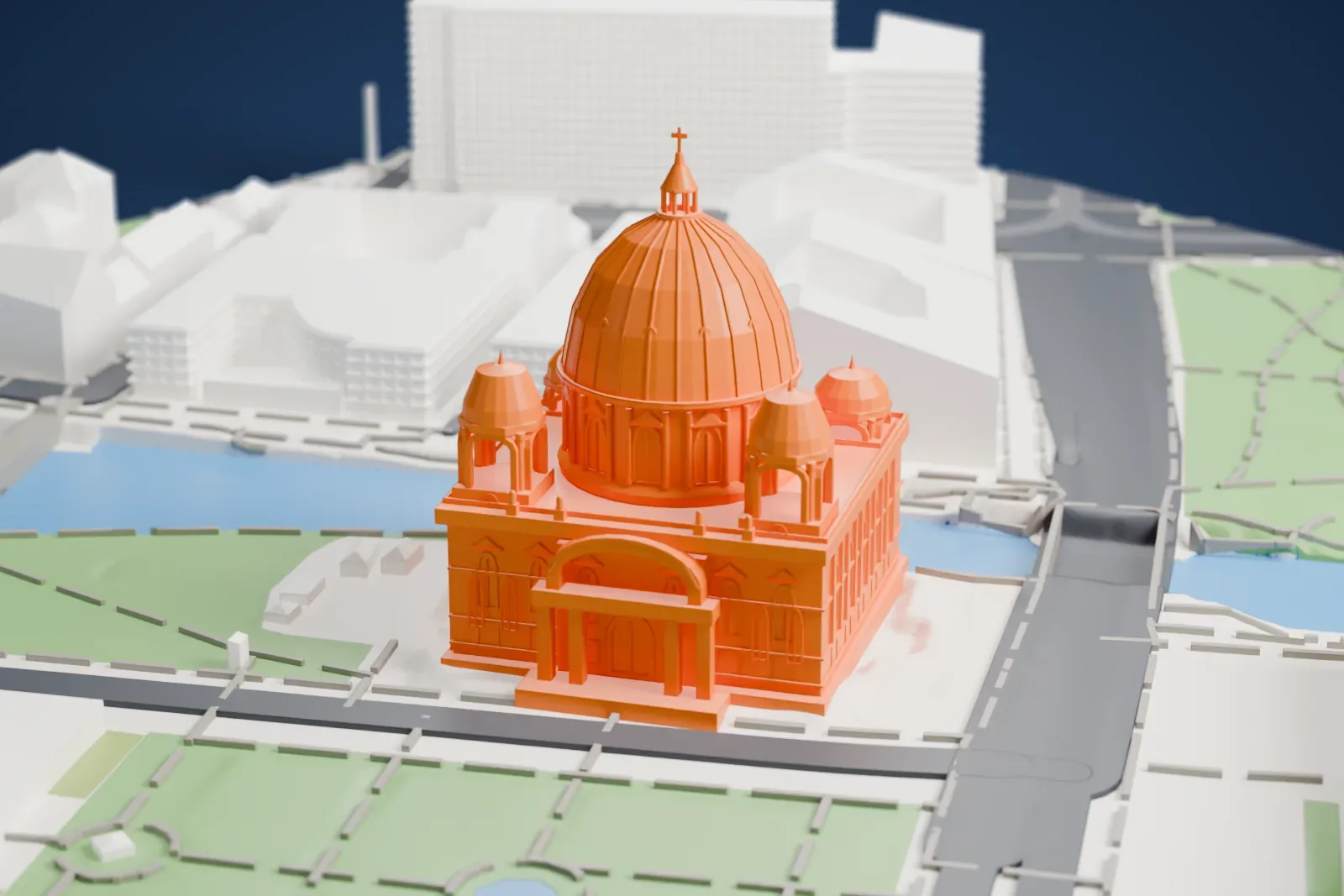 A white 3D print of Berlin Cathedral, a large church with a tall central dome and four small domed turrets, beside water and a green park with paths, with large buildings nearby.