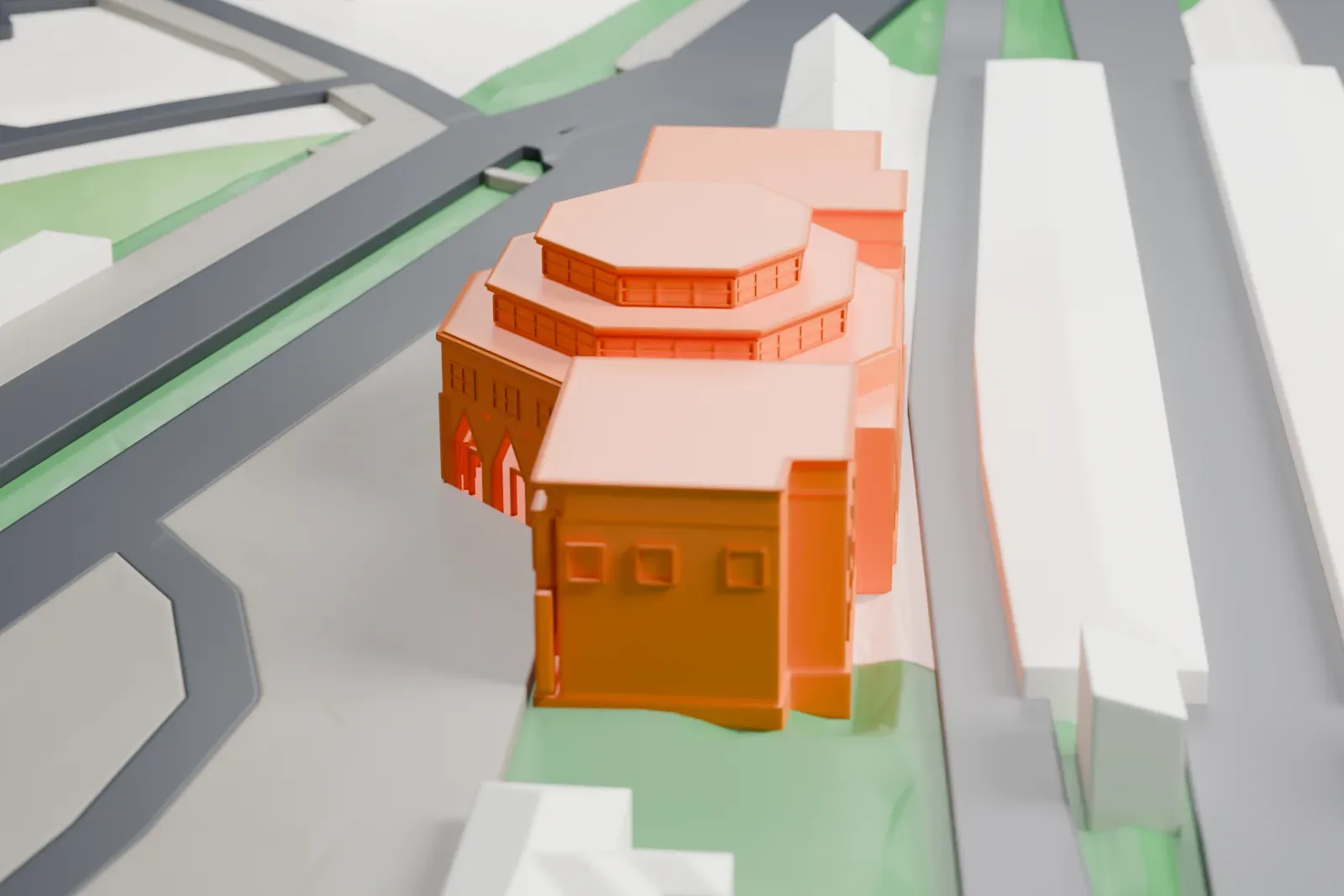 A white 3D print of Berlin-Wannsee station, with its faceted entrance hall, stepped lantern and flat-roofed wings, among the surrounding streets and buildings.