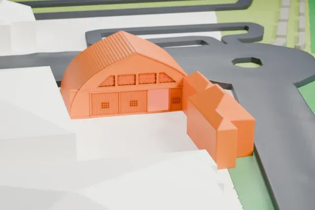 A white 3D print of the Bider Hangar at Bern Airport model in Bern, with the streets around it.