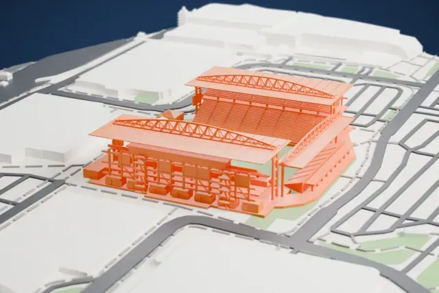 A white 3D print of BMO Field, a football stadium with roofed grandstands and arched roof trusses around a grass pitch, set among streets and large low buildings.