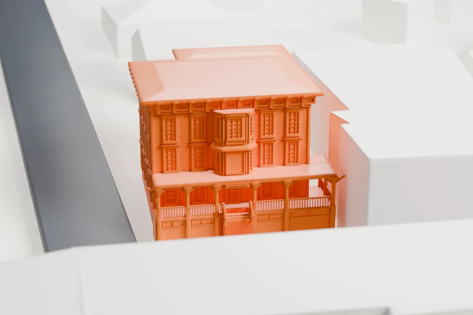 A white 3D print of the Boonton Public Library, a three-story building with a wide-eaved roof and a front porch, packed in among neighboring buildings along a street.