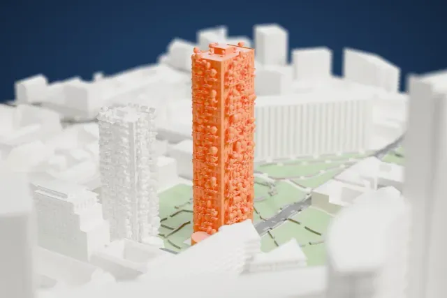 A white 3D print of the Bosco Verticale, two tall towers of different heights with small trees on their balconies, standing among park areas, roads and taller buildings nearby.
