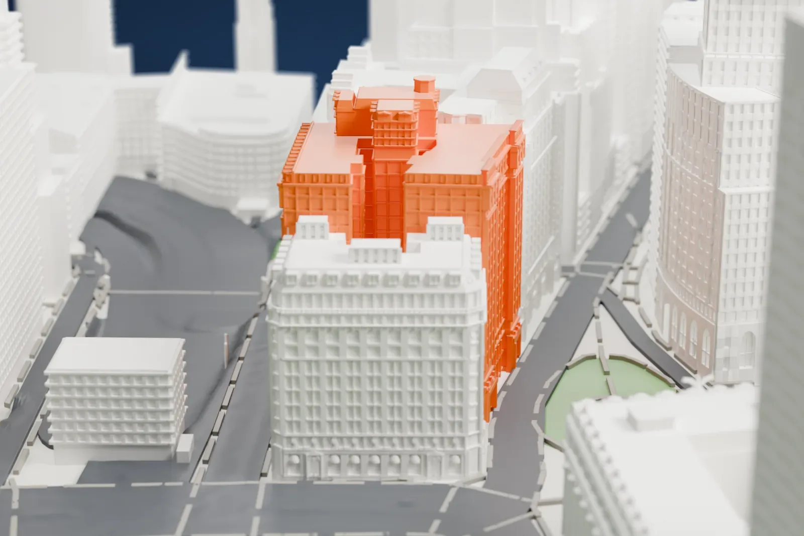 A white 3D print of the Bowling Green Offices Building, a tall ornate block with a smaller tower on top, among dense tall buildings and a park.