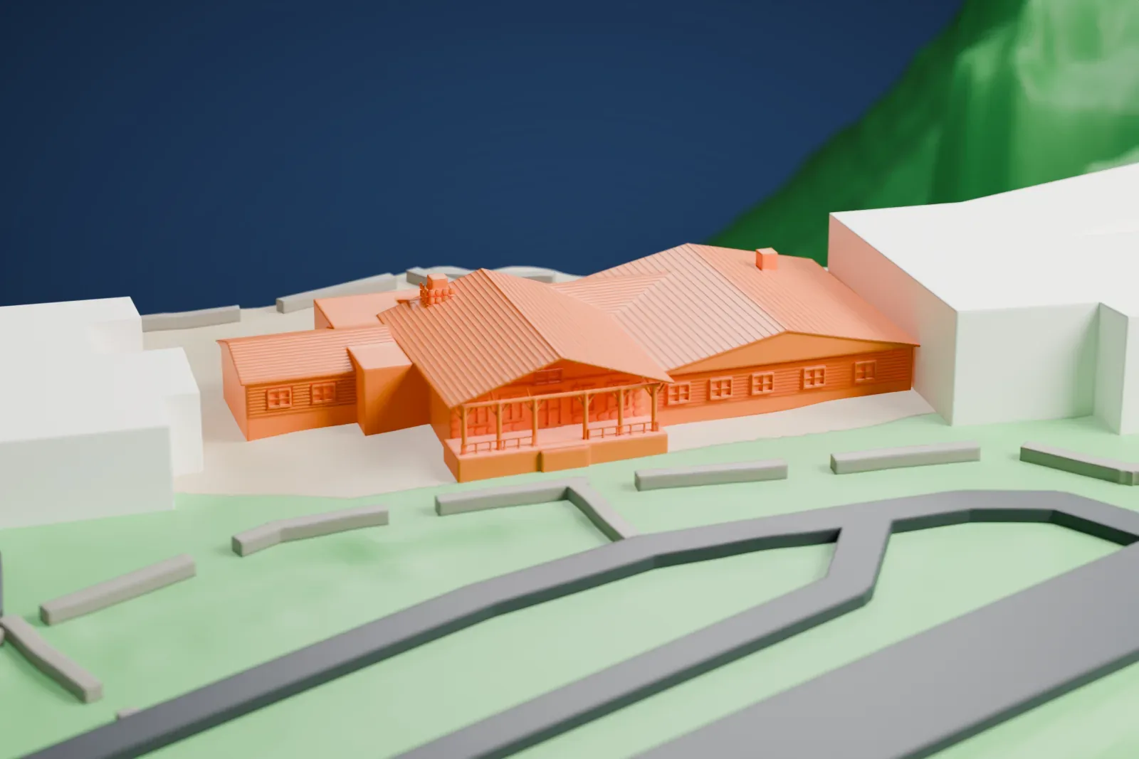A white 3D print of the Bright Angel Lodge with layered roofs and a covered porch, beside steep terrain, neighboring buildings, roads, and green space.