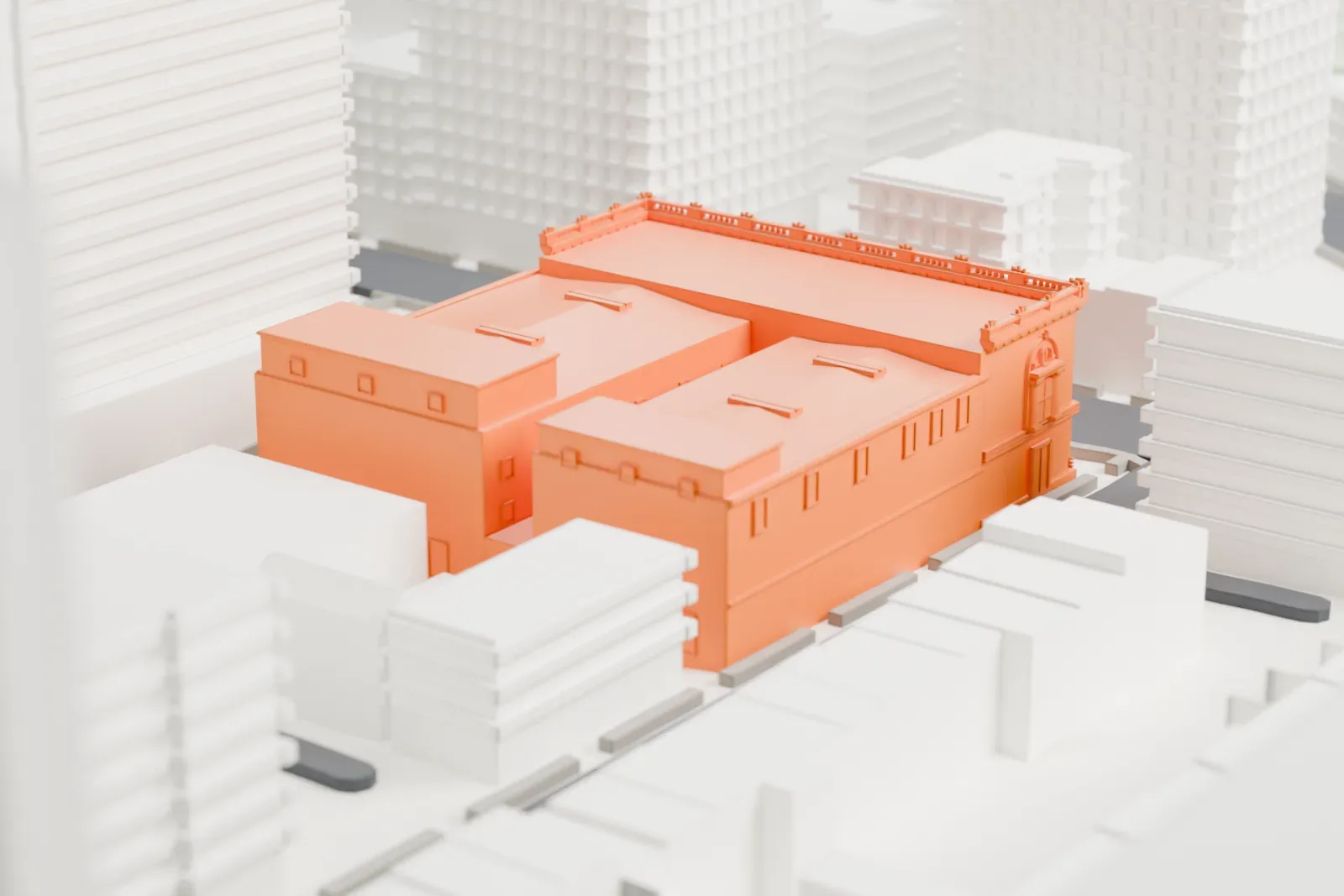 A white 3D print of the Brooklyn Academy of Music, a block-sized building with an ornate street facade and two long roofs, between city streets and a tall neighboring tower.