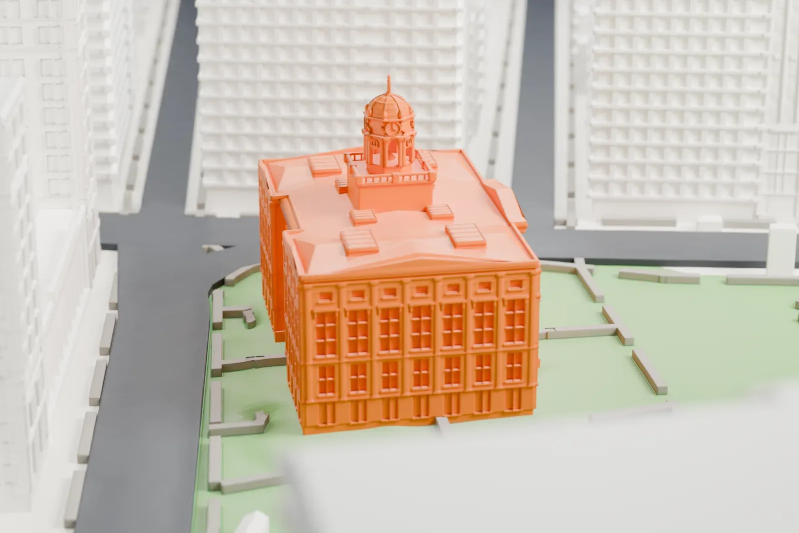 A white 3D print of Brooklyn Borough Hall, a columned building with a small domed cupola, set on a green plaza among taller buildings.