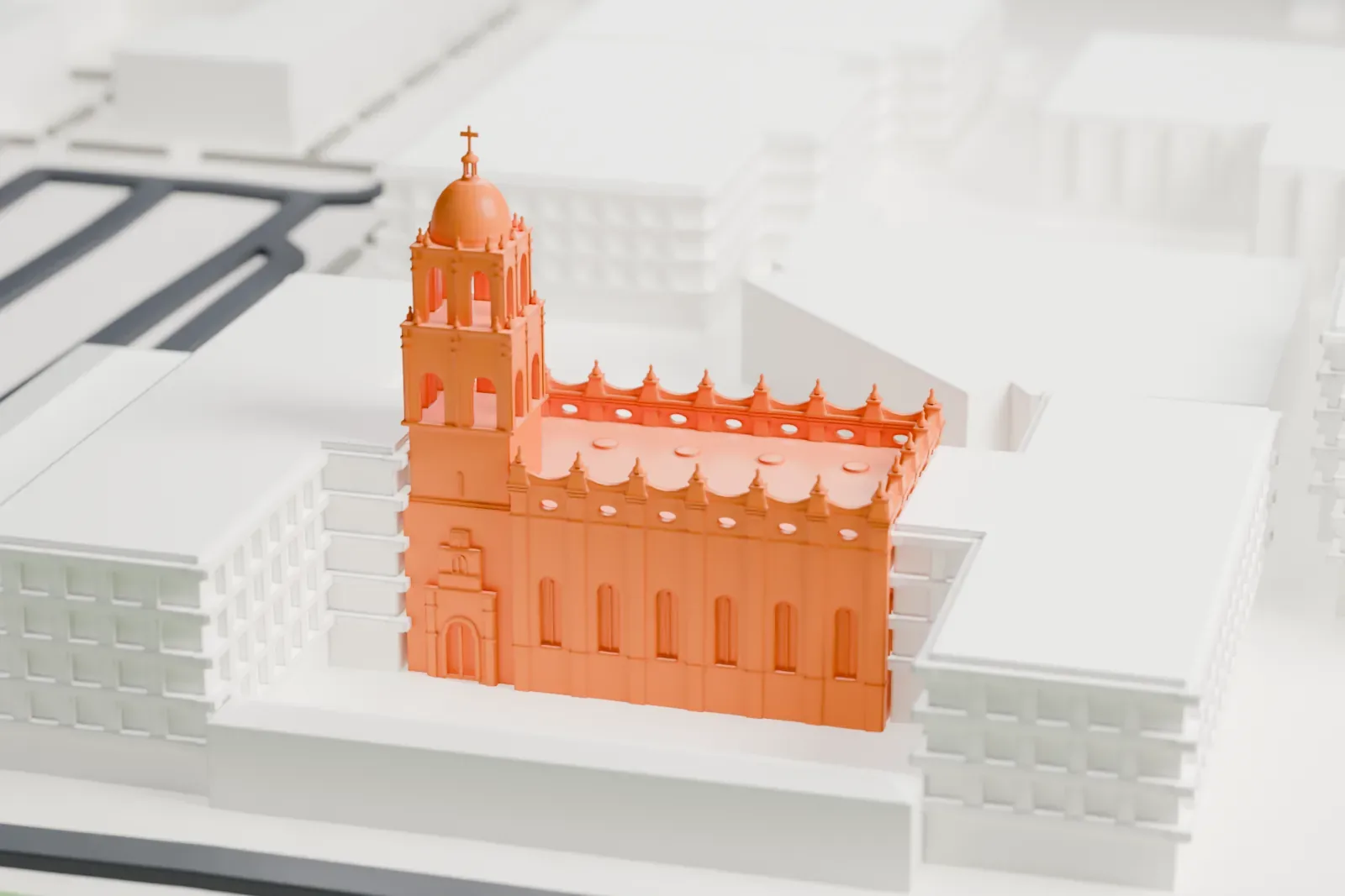 A white 3D print of the Brophy College Chapel, a square building with a domed bell tower and an ornate roofline, set among campus buildings.