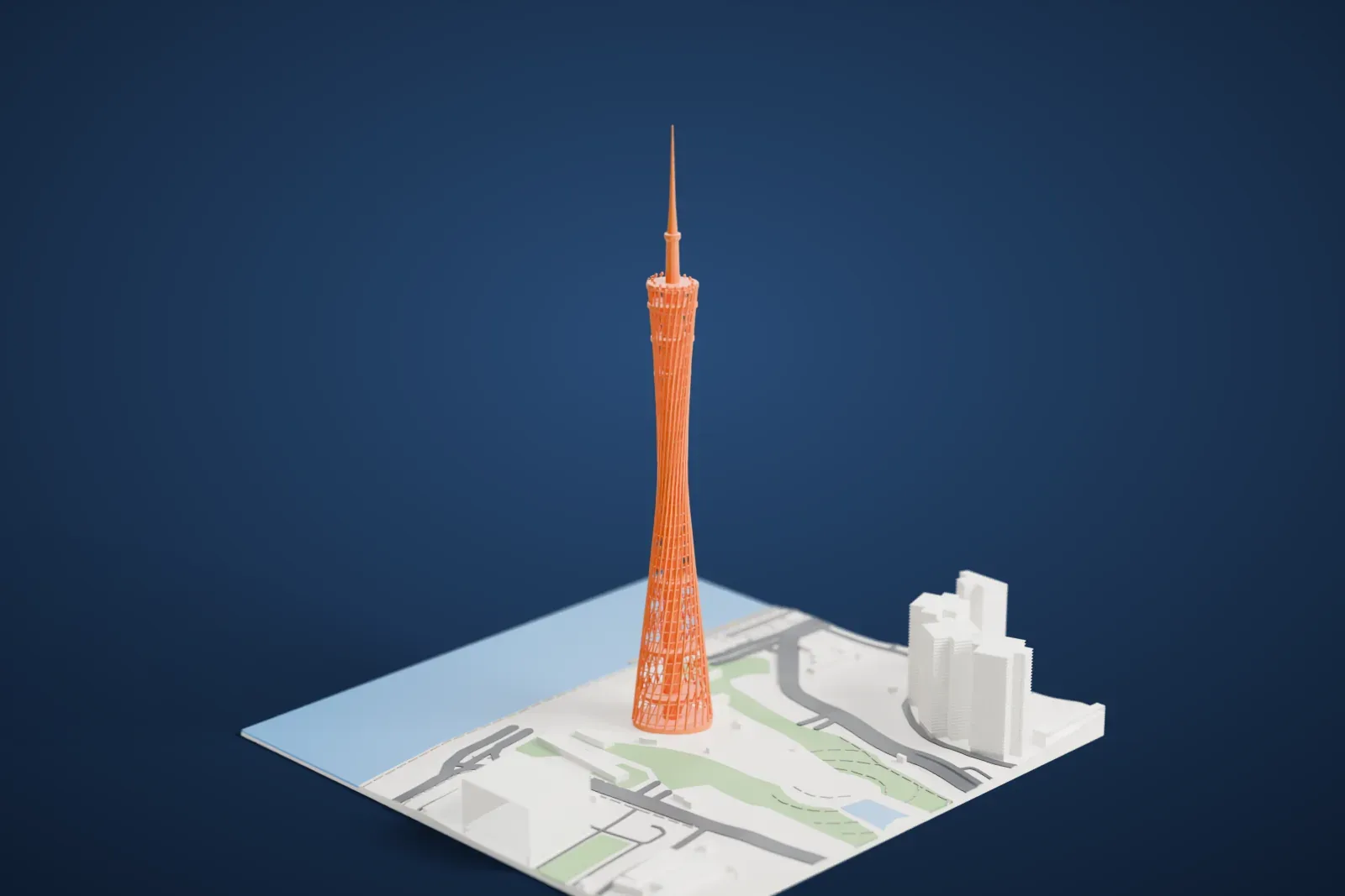 A white 3D print of the Canton Tower, a tall open-lattice tower that narrows at the waist and ends in a thin mast, standing beside open water and a park with tall buildings nearby.