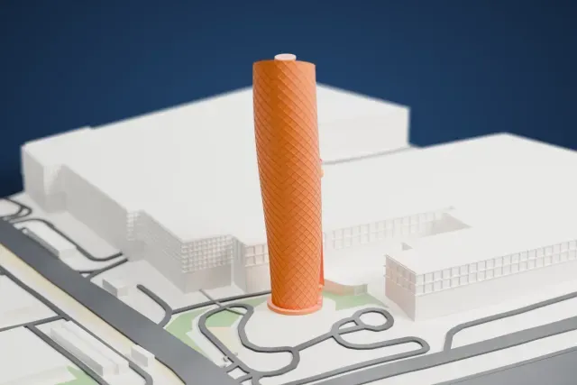 A white 3D print of the leaning Capital Gate tower beside a large low building, with roads and a shoreline nearby.