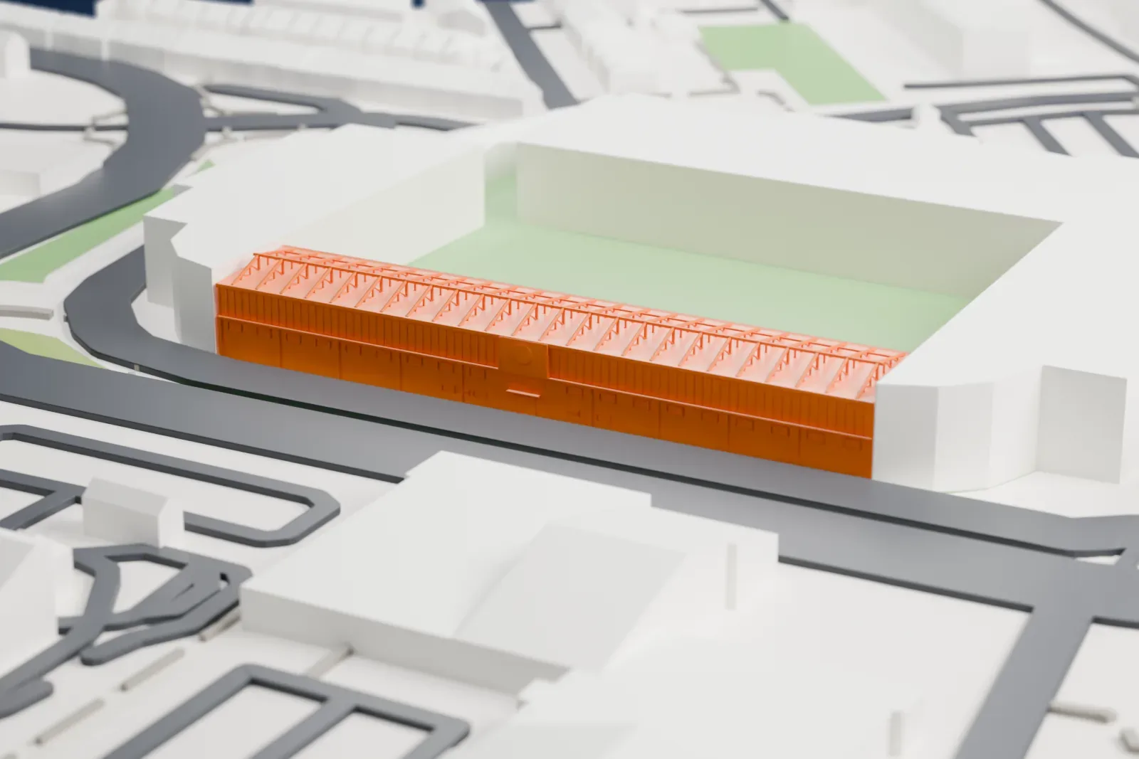 A white 3D print of the City Stand at Carrow Road, a long, low stand with a flat roof and rooftop steel trusses, standing among streets and buildings.