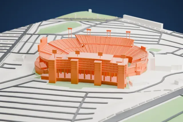 A white 3D print of Carter–Finley Stadium, a bowl of curved seating with a tall tiered tower on one side, surrounded by roads and open ground.