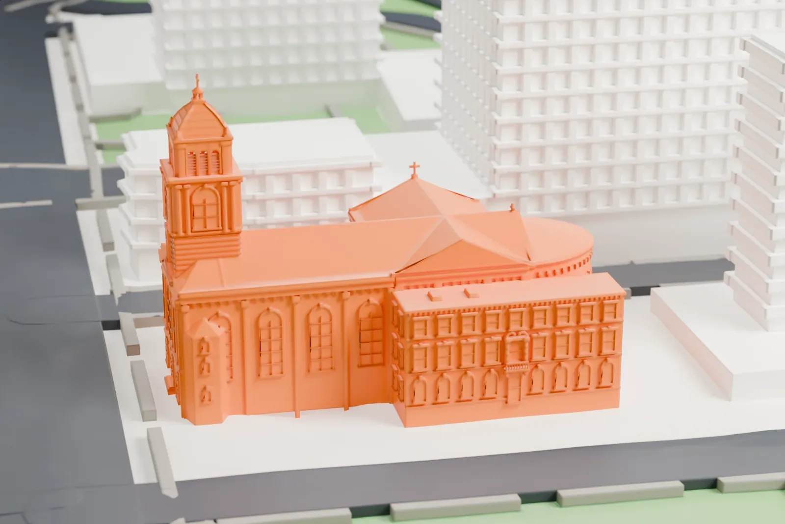 A white 3D print of the Cathedral Basilica of St. James, a church with a domed bell tower and a rounded rear end, hemmed in by taller buildings and streets.