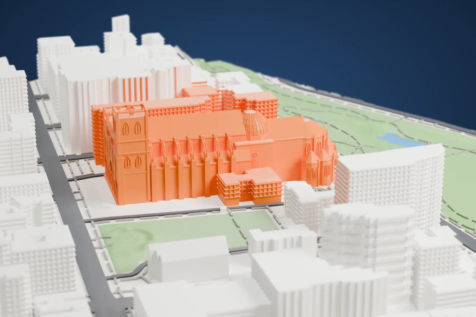 A white 3D print of the Cathedral of St John the Divine, a long church with a domed crossing, a rounded east end and arched buttresses along the nave, hemmed in by tall buildings and green lawns.