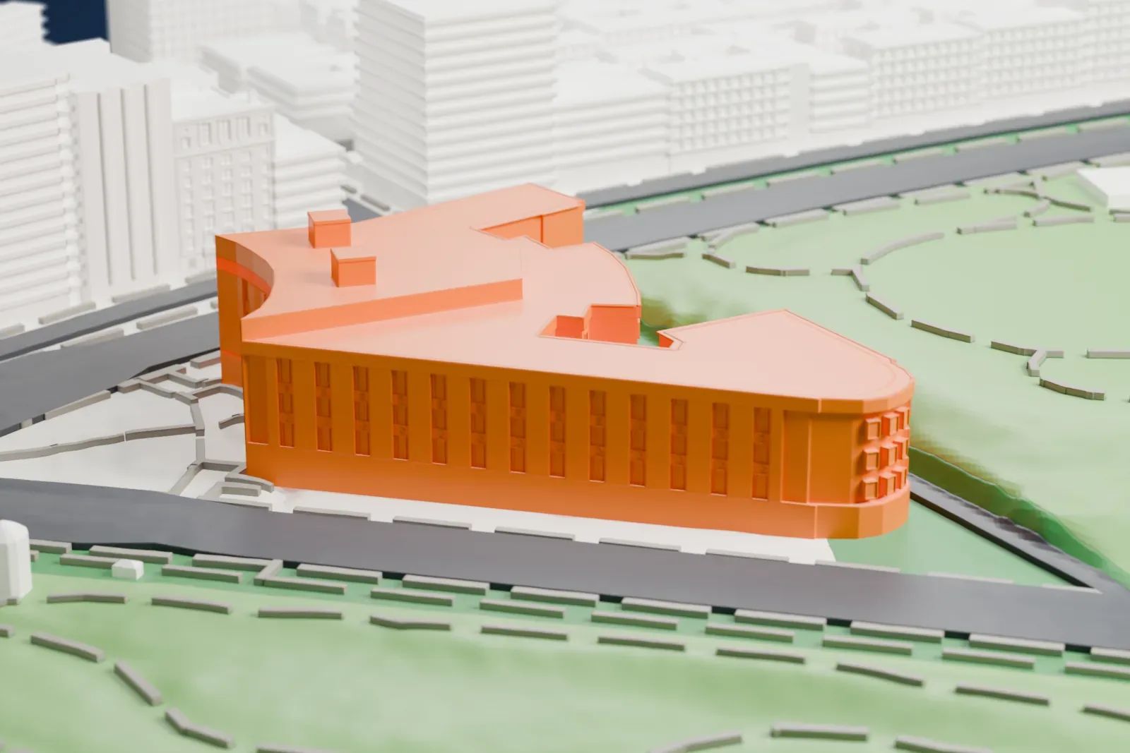 A white 3D print of the Central Library, a wedge-shaped building with a curved corner and rooftop boxes, between wide roads and the green, path-lined slopes of a park.