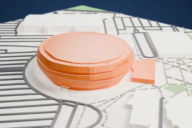 A white 3D print of Centre Vidéotron, a rounded, oval arena with banded walls and a broad flat roof, surrounded by streets, looping roads and low buildings.