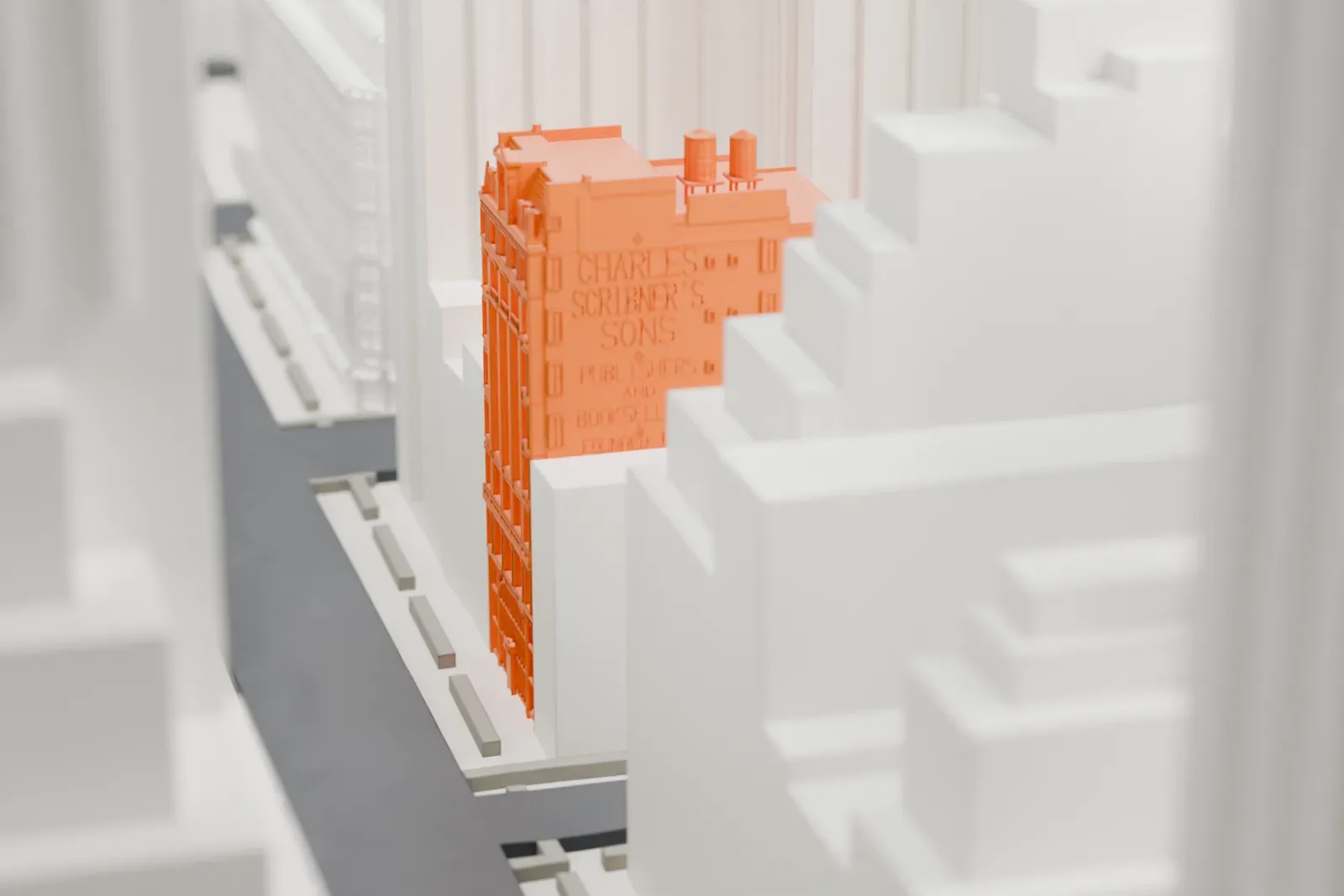 A white 3D print of the Charles Scribner's Sons Building, a narrow building whose upper floors show between much taller buildings.