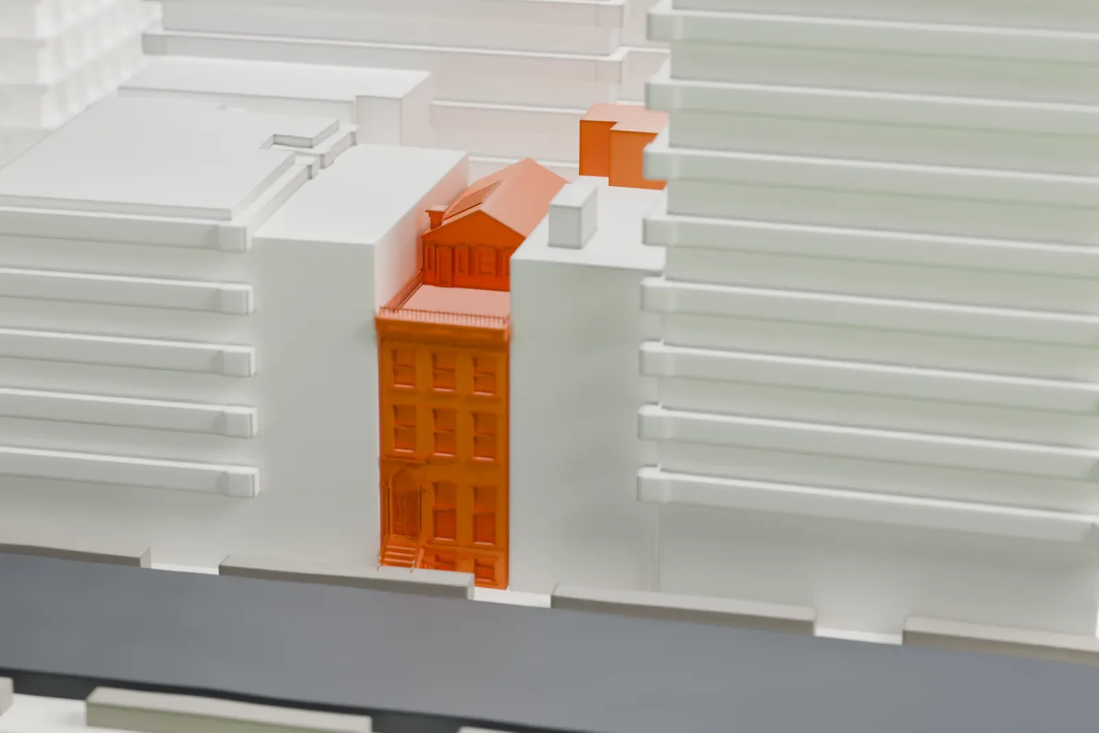 A white 3D print of the Charlie Parker Residence, a narrow brownstone rowhouse with a stoop, set between much larger buildings beside a street.