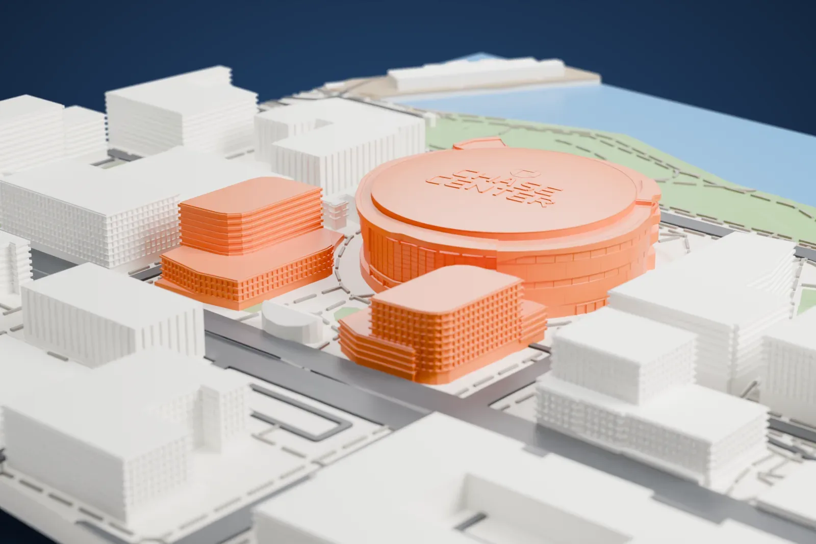 A white 3D print of Chase Center, a round arena with a flat circular roof carrying raised lettering, surrounded by city blocks, with a green waterfront strip and water beyond.